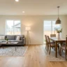 How to style an open plan dining and living area – featured image showing living zone with sectional and rug, dining zone with table and pendant light.