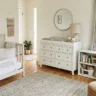 How to design a nursery that grows with your child – featured image of a neutral, adaptable nursery with convertible bed, dresser, open shelves, and blackout curtains.