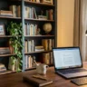 Home office bookshelf styling for video calls – featured image of a styled bookshelf behind a desk with laptop and warm lighting.