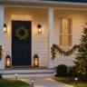 Christmas exterior lighting ideas that look elegant – featured image of a home with lit wreath, lanterns, garland, tree lights, and path lights.