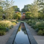 garden water features – a sleek dark slate rill reflecting sky and silver birch trees in a modern garden.